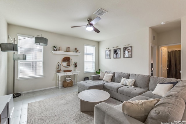 living room featuring light tile patterned floors, ceiling fan, visible vents, and baseboards