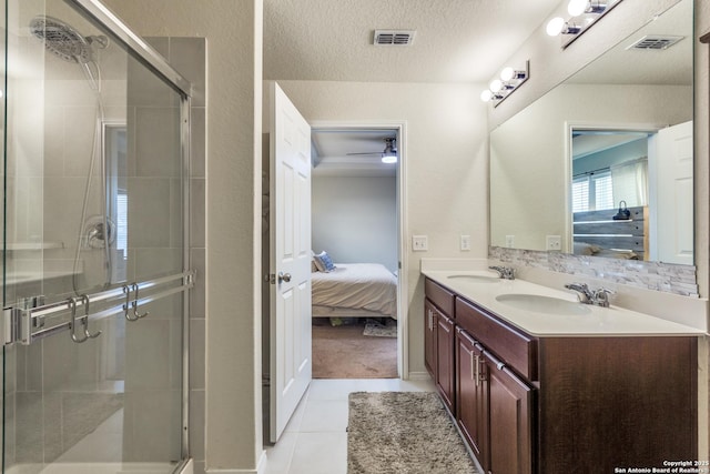 bathroom with tile patterned flooring, a sink, a textured ceiling, and ensuite bathroom