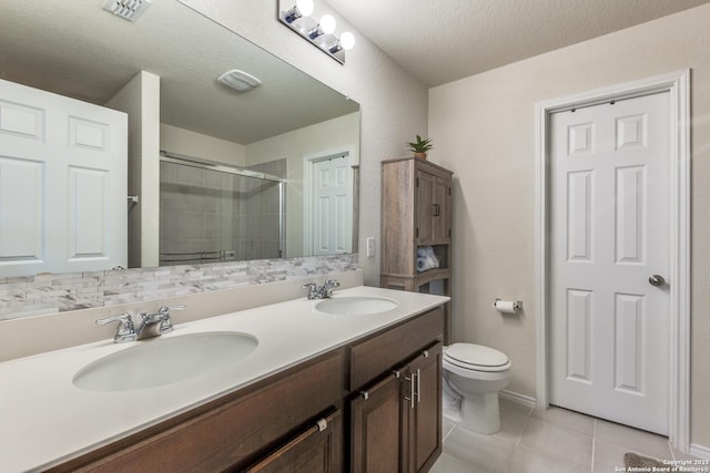 bathroom with double vanity, tiled shower, tile patterned flooring, and a sink