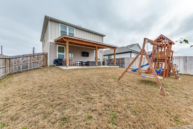 back of property with board and batten siding, a yard, a playground, and a patio