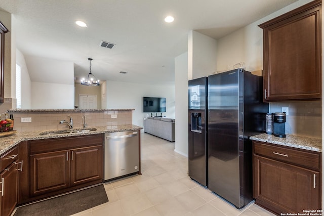 kitchen featuring stainless steel appliances, visible vents, hanging light fixtures, a sink, and light stone countertops