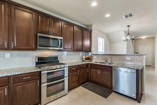 kitchen with visible vents, appliances with stainless steel finishes, light stone counters, decorative light fixtures, and a sink