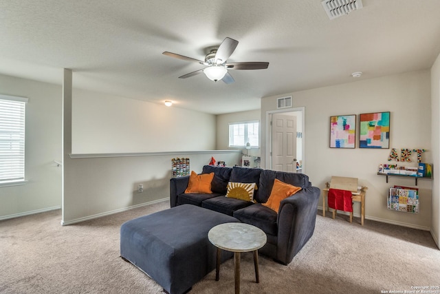 carpeted living area featuring baseboards, visible vents, and a ceiling fan