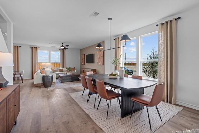 dining room featuring light wood-style floors, ceiling fan, visible vents, and baseboards