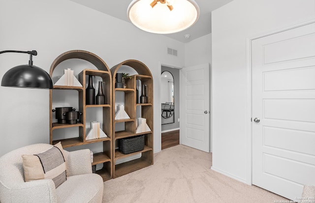 living area featuring light colored carpet, visible vents, and baseboards