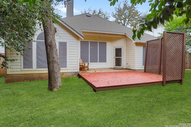 back of property featuring roof with shingles, a lawn, a chimney, and a wooden deck