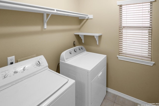 clothes washing area with light tile patterned floors, laundry area, baseboards, and washer and dryer