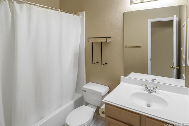 bathroom with a textured wall, shower / bath combo with shower curtain, vanity, and toilet