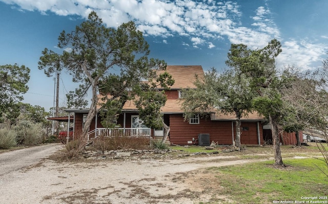 rustic home with driveway, covered porch, and central AC unit