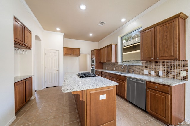 kitchen with light stone counters, stainless steel appliances, a sink, a kitchen island, and brown cabinetry