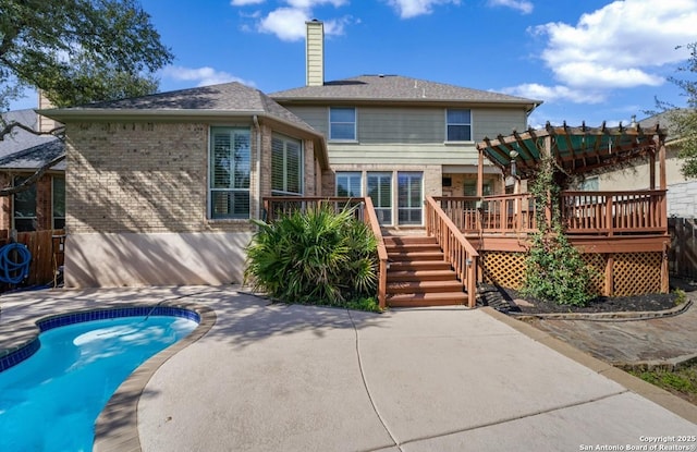 back of house featuring a deck, brick siding, an outdoor pool, a pergola, and a chimney