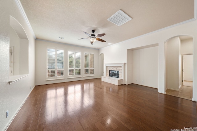 unfurnished living room with a fireplace, visible vents, dark wood-type flooring, ornamental molding, and a textured ceiling