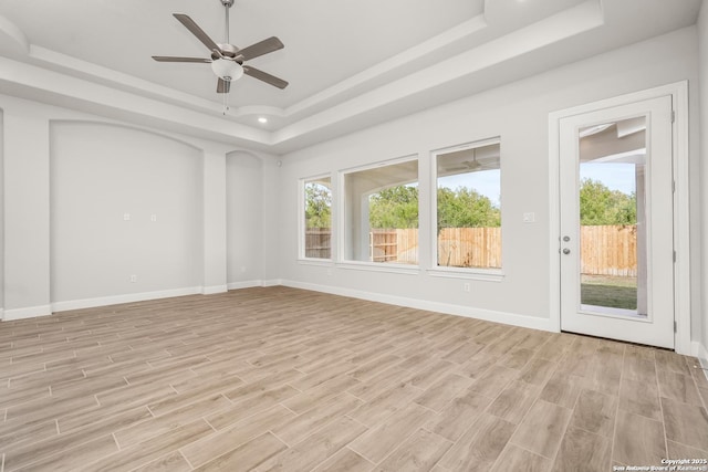 spare room with light wood-style floors, a raised ceiling, and baseboards