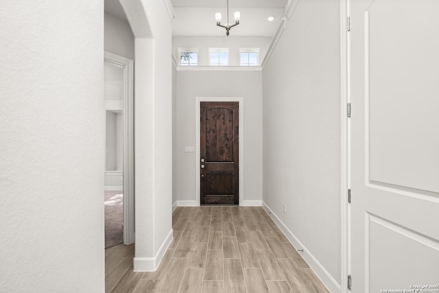 entryway featuring light wood finished floors, baseboards, and an inviting chandelier