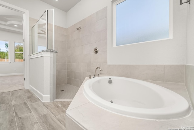 full bathroom featuring wood finish floors, baseboards, a bath, and walk in shower