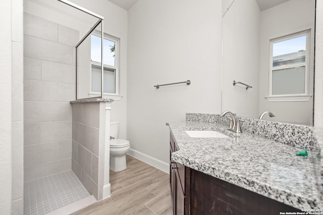 bathroom featuring a stall shower, baseboards, toilet, wood finished floors, and vanity