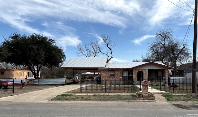 view of front facade with driveway, a fenced front yard, metal roof, and a carport