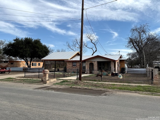 view of front of property featuring a fenced front yard, metal roof, and brick siding