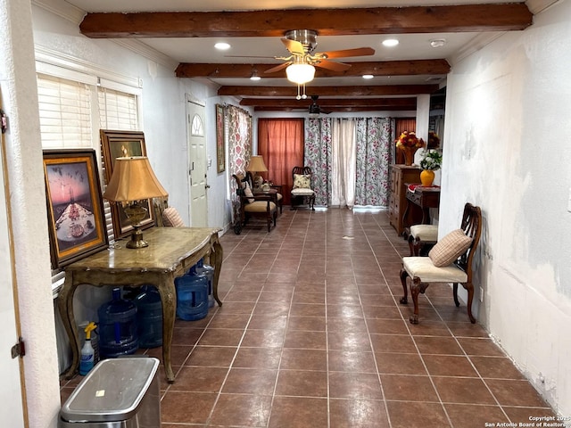 living area featuring ceiling fan, beamed ceiling, and dark tile patterned flooring