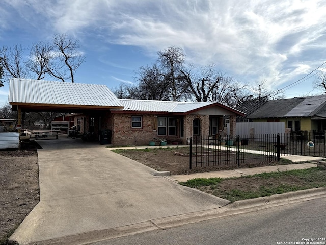 view of front facade with driveway, metal roof, an attached carport, fence, and brick siding