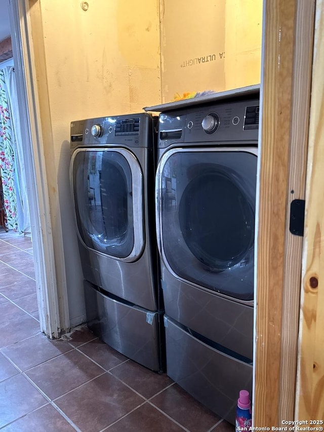 washroom featuring laundry area, dark tile patterned floors, and washing machine and dryer