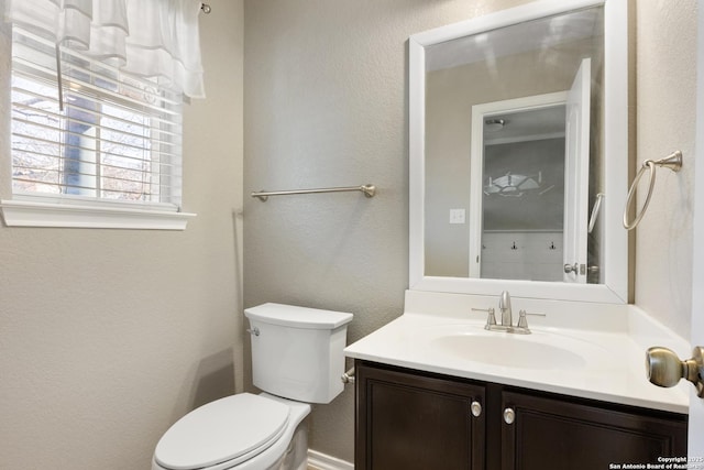 bathroom featuring a textured wall, vanity, and toilet