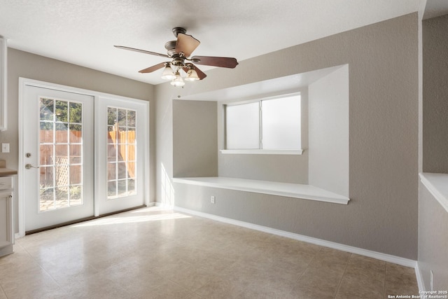 empty room featuring ceiling fan and baseboards