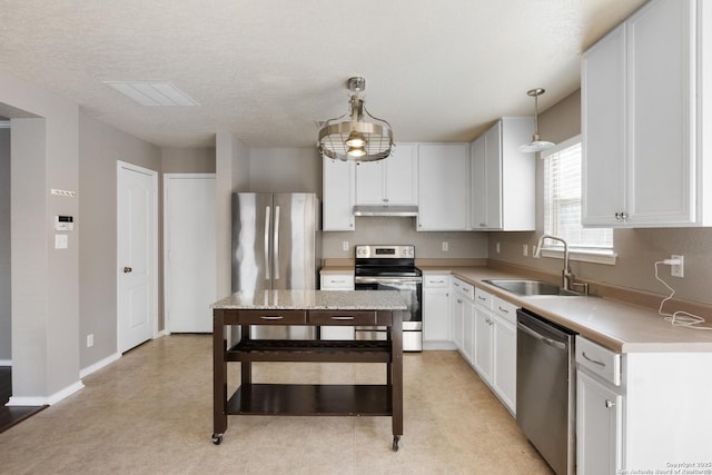 kitchen featuring pendant lighting, light countertops, appliances with stainless steel finishes, a sink, and under cabinet range hood