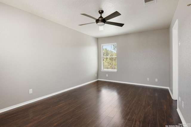 spare room featuring dark wood-type flooring, visible vents, ceiling fan, and baseboards