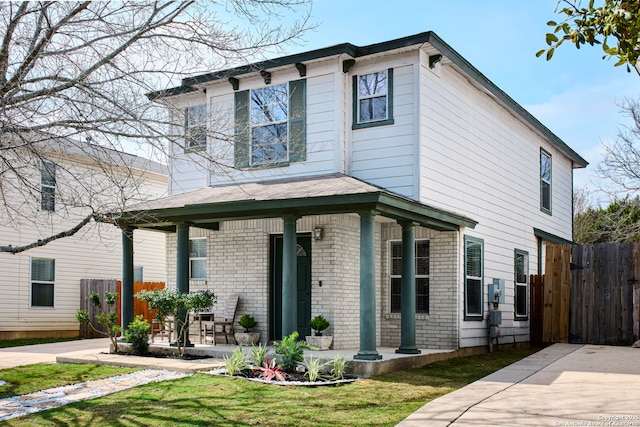 view of front of home with brick siding, a front lawn, and fence