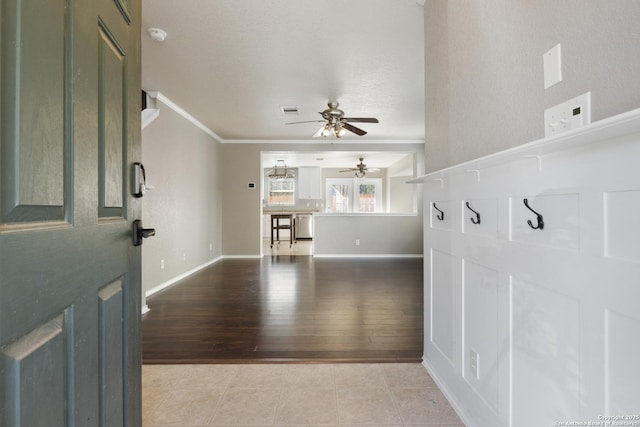 foyer featuring light tile patterned floors, visible vents, baseboards, and crown molding