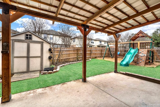 view of patio featuring a fenced backyard, a storage unit, a playground, and an outbuilding