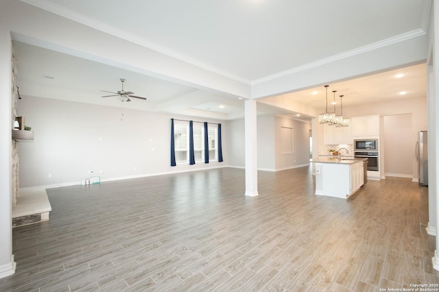 unfurnished living room with light wood finished floors, recessed lighting, a ceiling fan, a glass covered fireplace, and baseboards