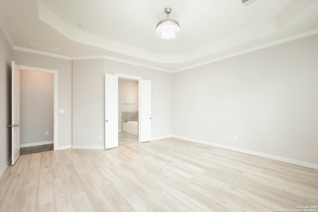 unfurnished bedroom with light wood-style flooring, baseboards, a raised ceiling, ensuite bath, and crown molding