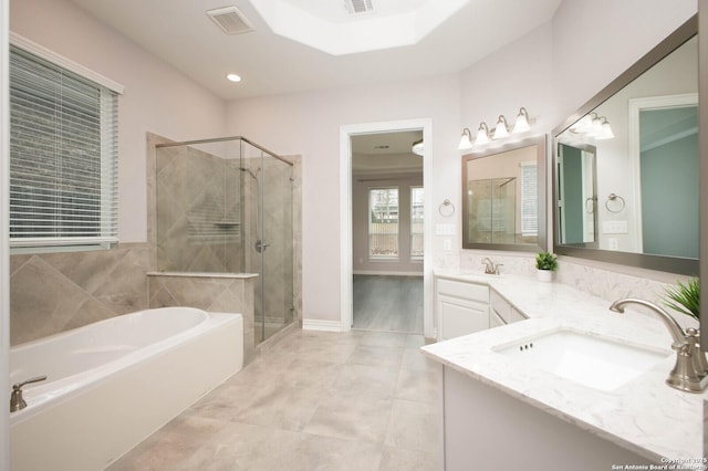 bathroom featuring a garden tub, double vanity, visible vents, a sink, and a shower stall