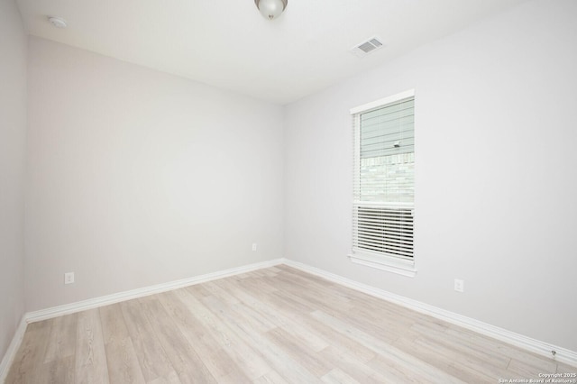 spare room featuring light wood-type flooring, visible vents, and baseboards