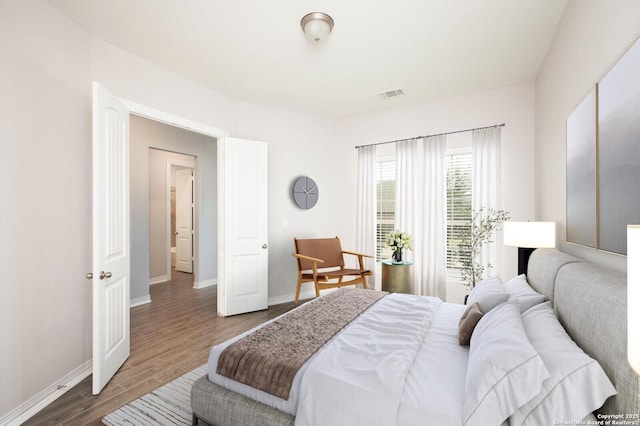 bedroom featuring wood finished floors, visible vents, and baseboards