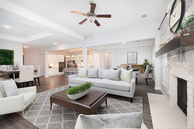 living room featuring a fireplace with raised hearth, recessed lighting, dark wood-type flooring, visible vents, and baseboards