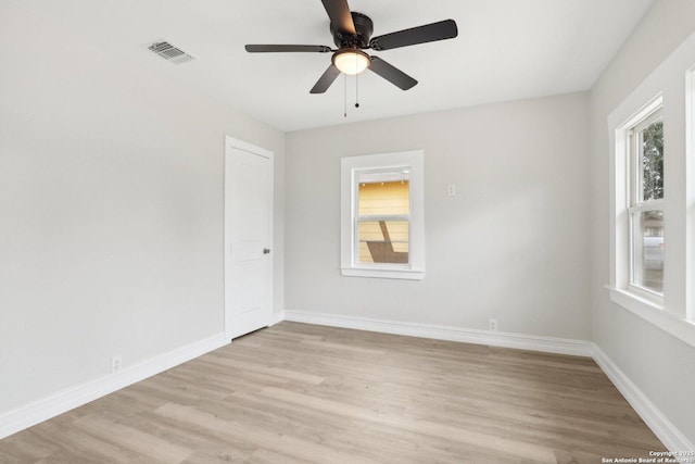 spare room featuring light wood-type flooring, a healthy amount of sunlight, visible vents, and baseboards