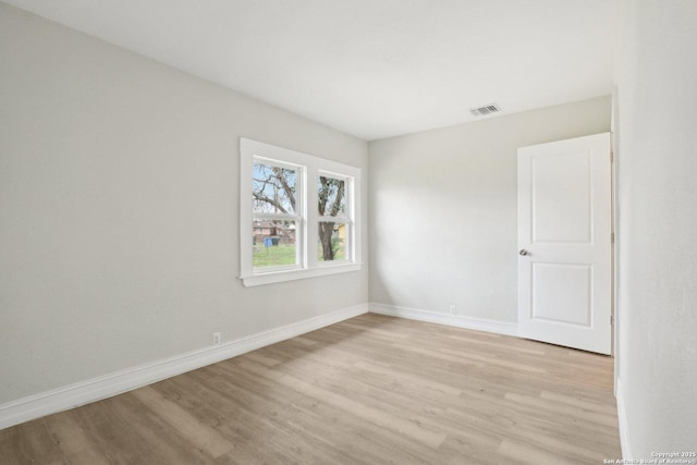 spare room featuring light wood-style floors, visible vents, and baseboards