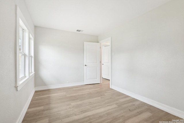 unfurnished room featuring baseboards, visible vents, and light wood-style floors