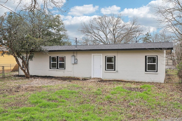 rear view of house with brick siding, a lawn, and fence