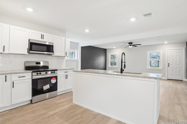 kitchen with an island with sink, white cabinetry, appliances with stainless steel finishes, and a sink