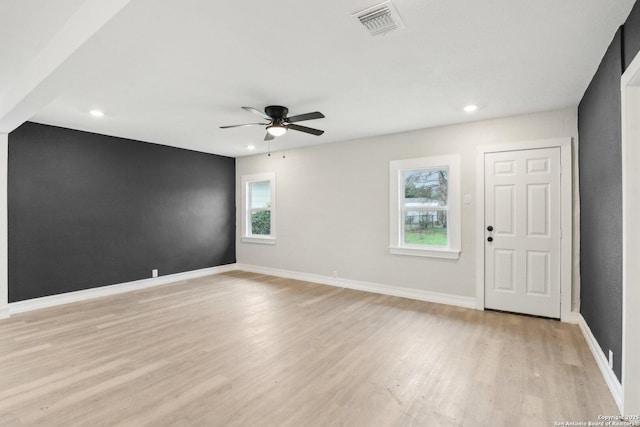 spare room featuring light wood-style floors, baseboards, visible vents, and a wealth of natural light