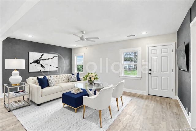 living area with light wood-type flooring, visible vents, ceiling fan, and baseboards