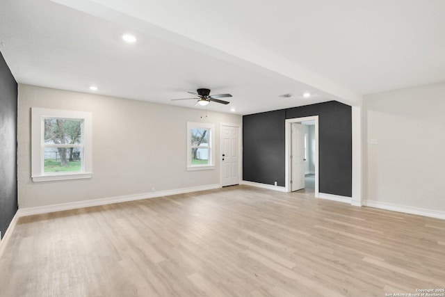 spare room featuring light wood-type flooring, visible vents, and baseboards