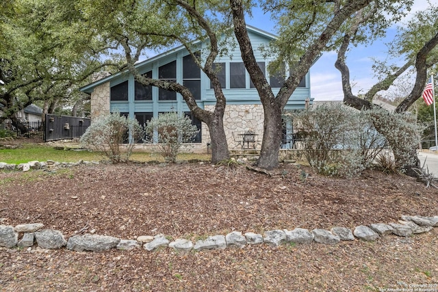 exterior space featuring stone siding, fence, and a sunroom