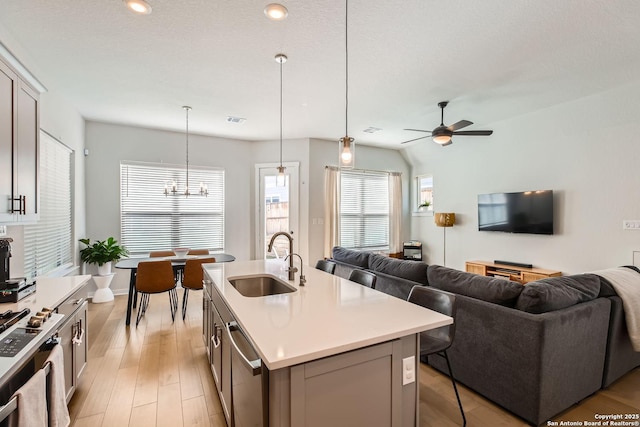 kitchen featuring a center island with sink, light countertops, a sink, and open floor plan