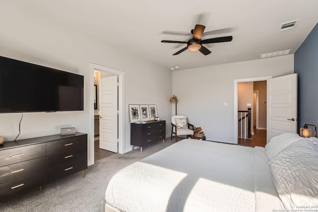 bedroom with connected bathroom, visible vents, dark colored carpet, and a ceiling fan