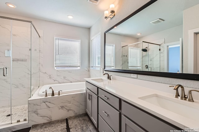 bathroom featuring a stall shower, double vanity, a sink, and a bath